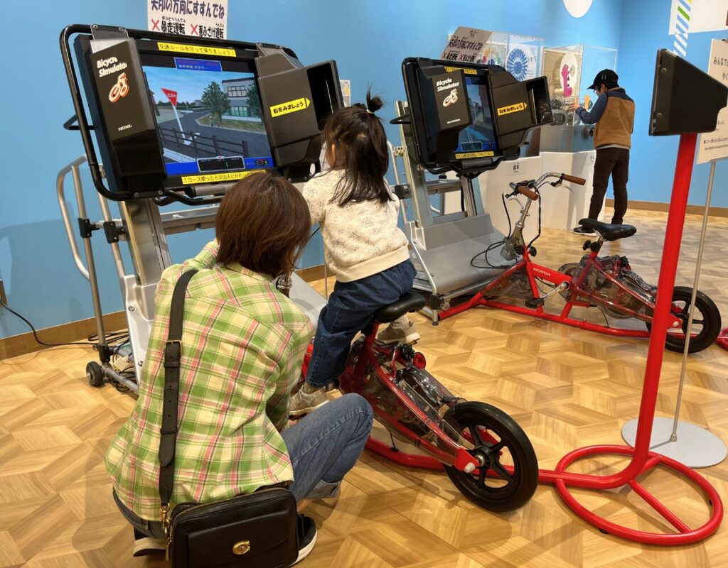 ながのこども館ながノビ!科学と創造の広場内の自転車シミュレーターで遊ぶ子供