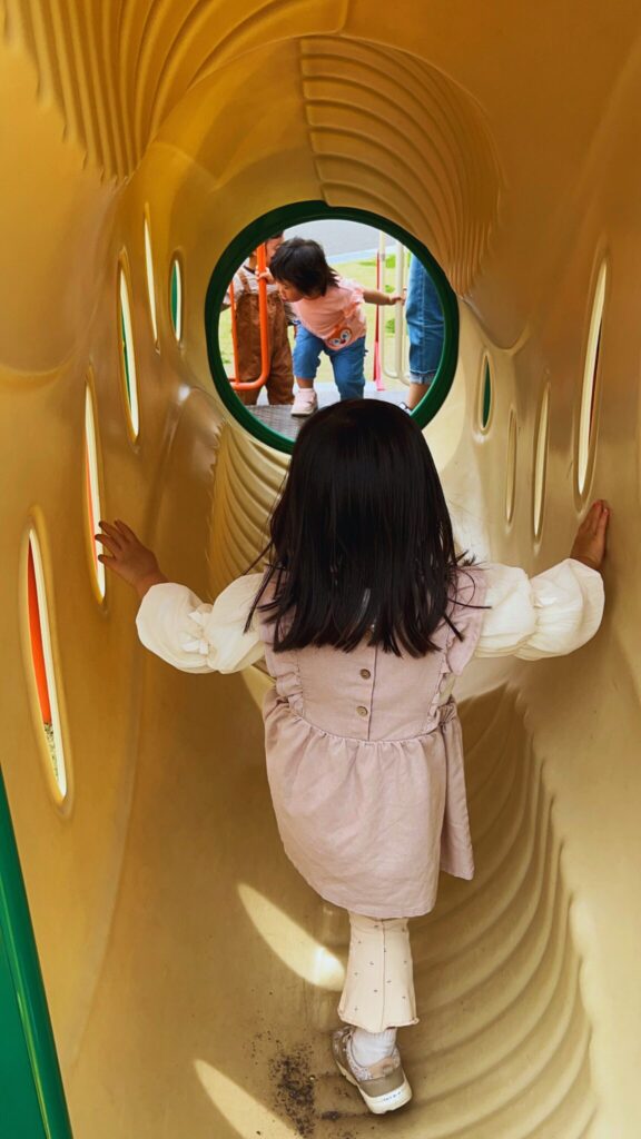 大間近隣公園(大間見晴らしの丘)の小学生向けの大型複合遊具のハチの巣を模したトンネルを通る子ども