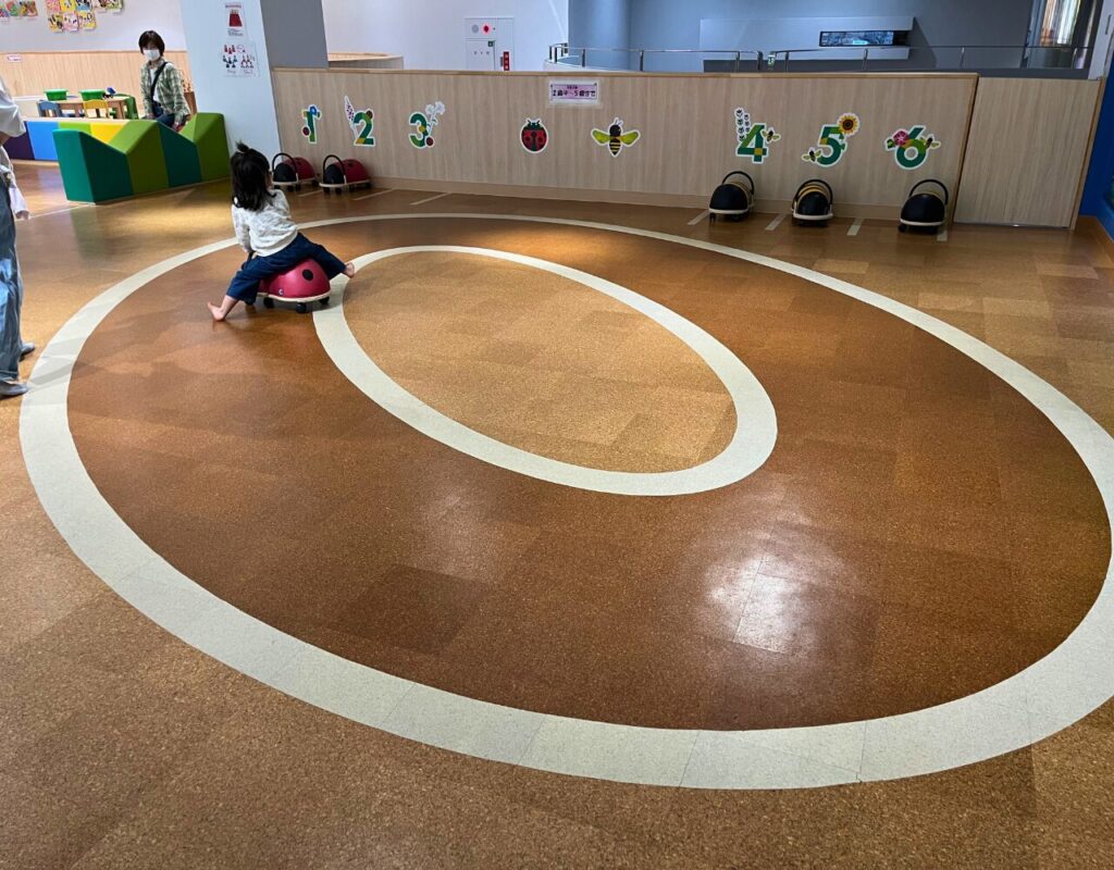 ながのこども館ながノビ!森の探検広場内の乗用玩具で遊ぶ子供