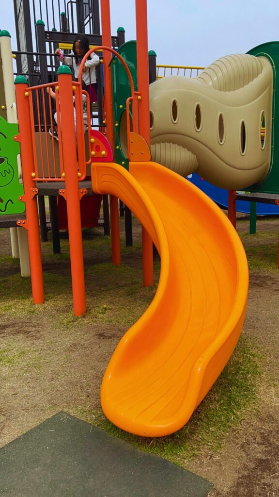 大間近隣公園(大間見晴らしの丘)の小学生向けの大型複合遊具の黄色い湾曲したすべり台
