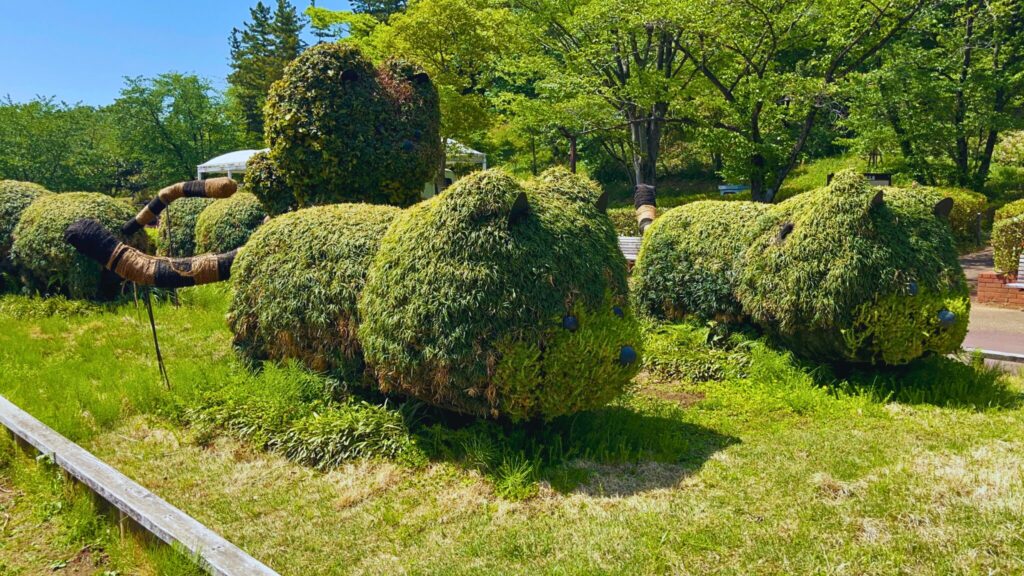 埼玉県子ども動物自然公園の草で覆われたアライグマのオブジェ