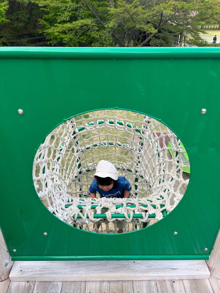 地附山公園の大型複合遊具-ネットトンネルで遊ぶ子ども