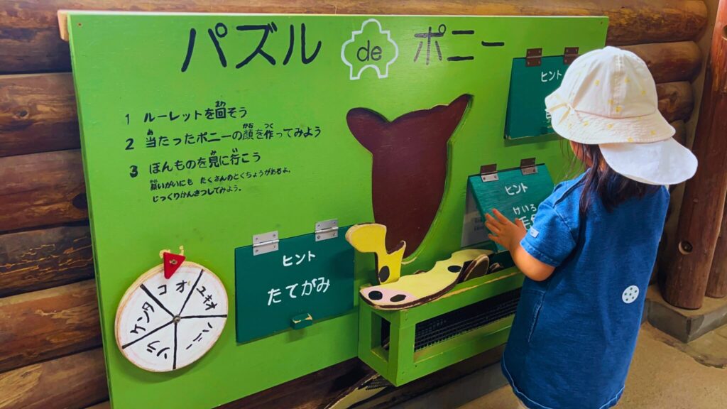 埼玉県子ども動物自然公園の馬小屋のポニーパズルで遊ぶ子ども