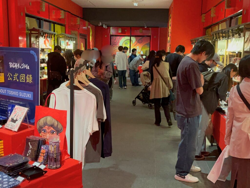 鈴木敏夫とジブリ展内の特設ショップでお土産を見る人々