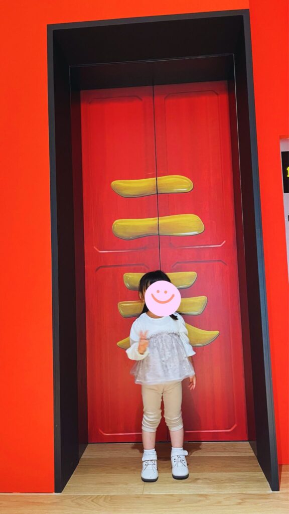 鈴木敏夫とジブリ展内の千と千尋の神隠しに登場するエレベーターの前で、ピースをする子ども